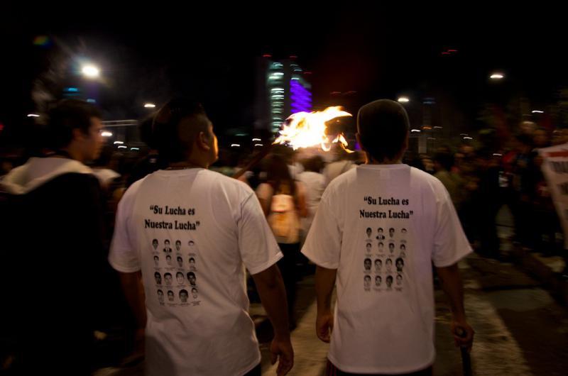 Junge Männer tragen T-Shirts mit Fotos der verschwundenen Studenten. Schriftzug: "Ihr Kampf ist unser Kampf"