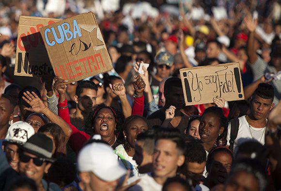 Teilnehmerinnen der Demonstration halten Schilder hoch: "Kuba gehört uns" und "Ich bin Fidel".