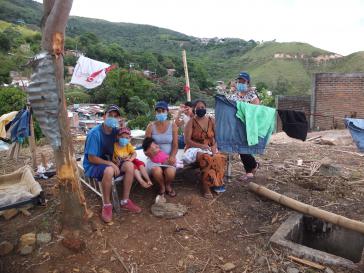 Eine Familie sitzt vor ihrer zerstörten Hütte in Siloé