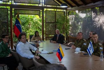 Venezolanische Regierungsvertreter sitzen an einem Tisch mit Soldaten des israelischen Militärs Venezolanische Regierungsvertreter sitzen an einem Tisch mit Soldaten des israelischen Militärs